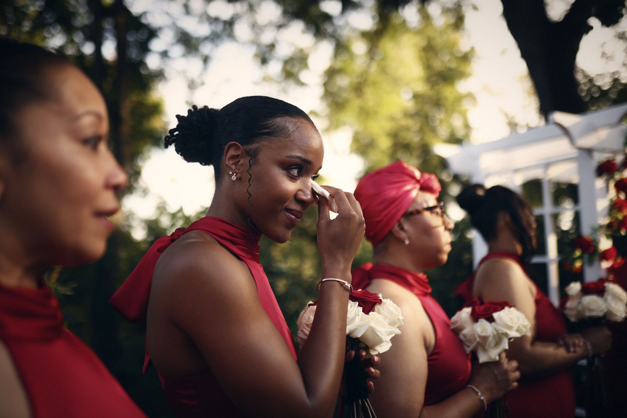 Bridesmaid in red wiping away tears during the ceremony