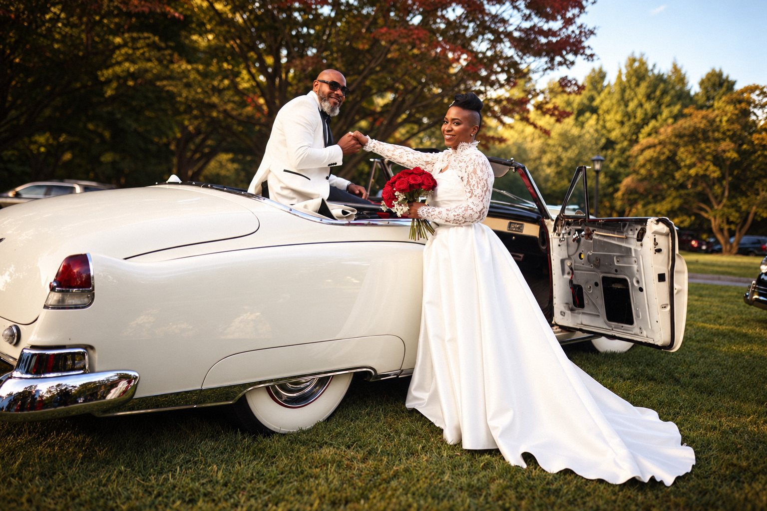 Bride with a long train taking the groom&rsquo;s hand beside a white vintage convertible