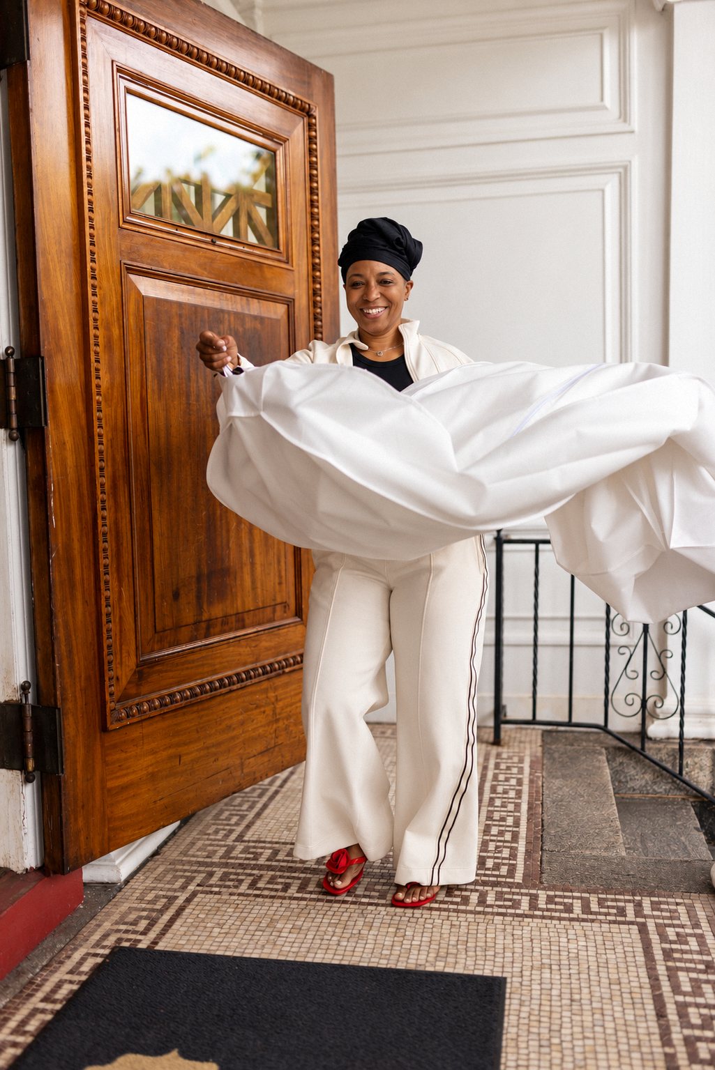 Bride laughing as she swings open her dress bag in a mosaic tiled entryway
