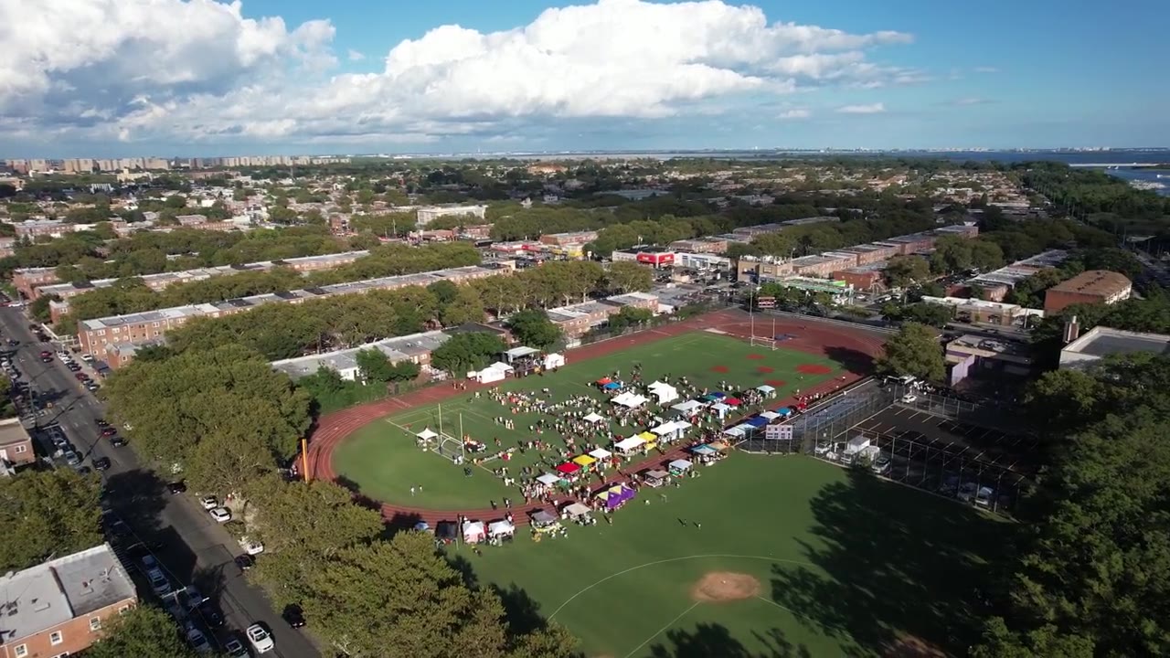 Aerial view of a festival on a ballfield surrounded by the city