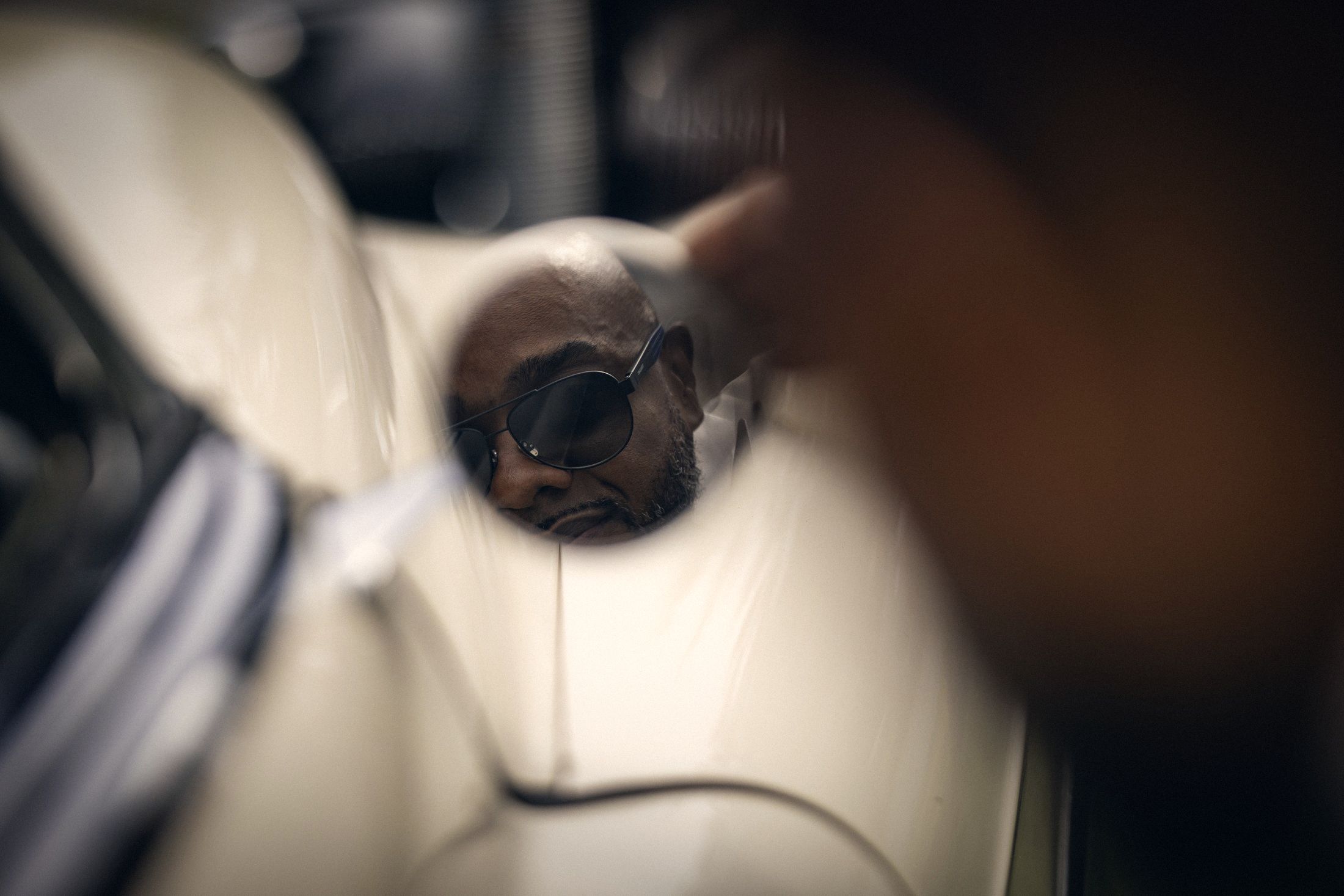 Groom in sunglasses reflected in a vintage car mirror