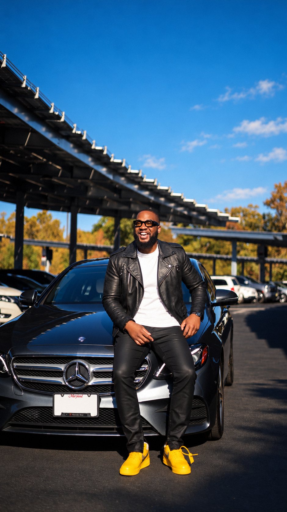 Man laughing while sitting on the hood of a Mercedes