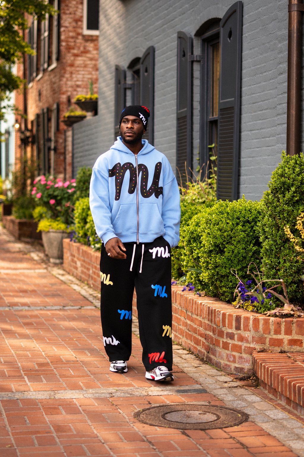 Man in a light blue hoodie walking down a brick sidewalk