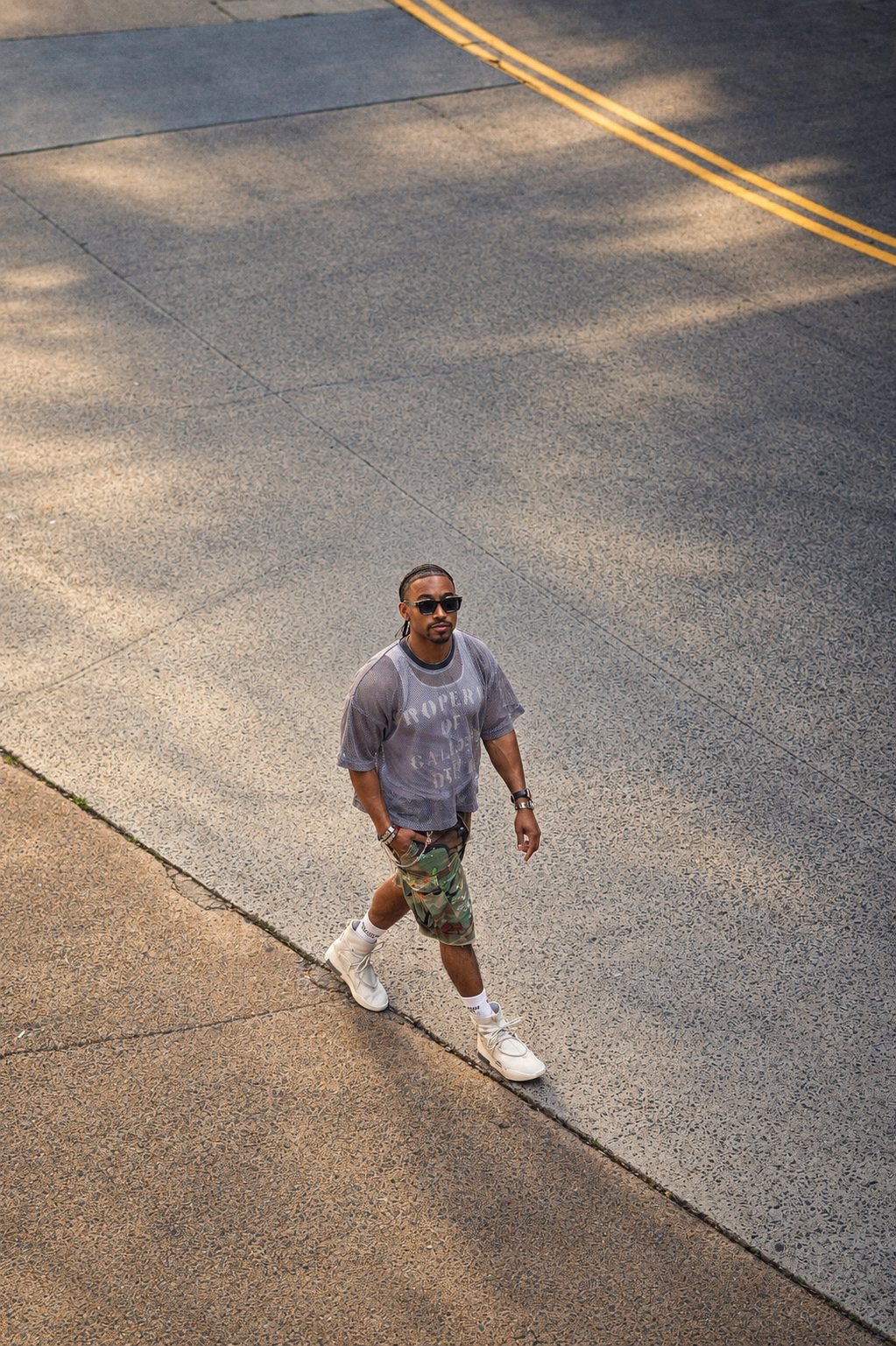 Overhead shot of a man walking across a sunlit street