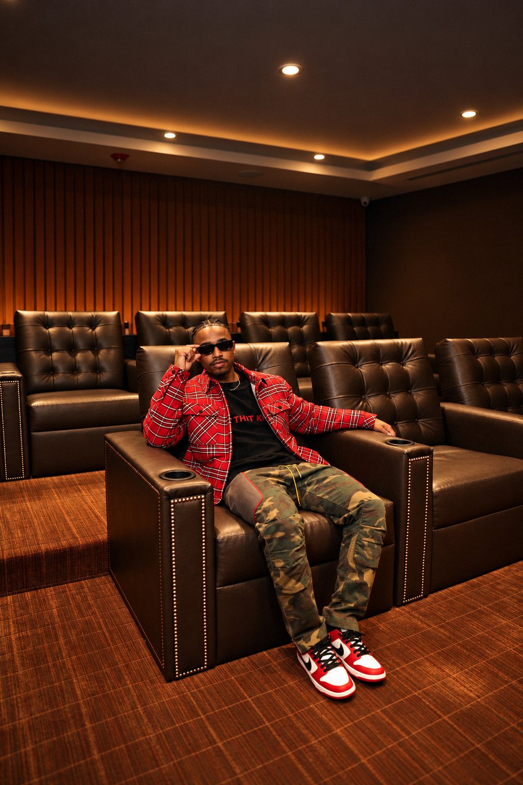 Man lounging in a leather home theater seat in a red plaid jacket