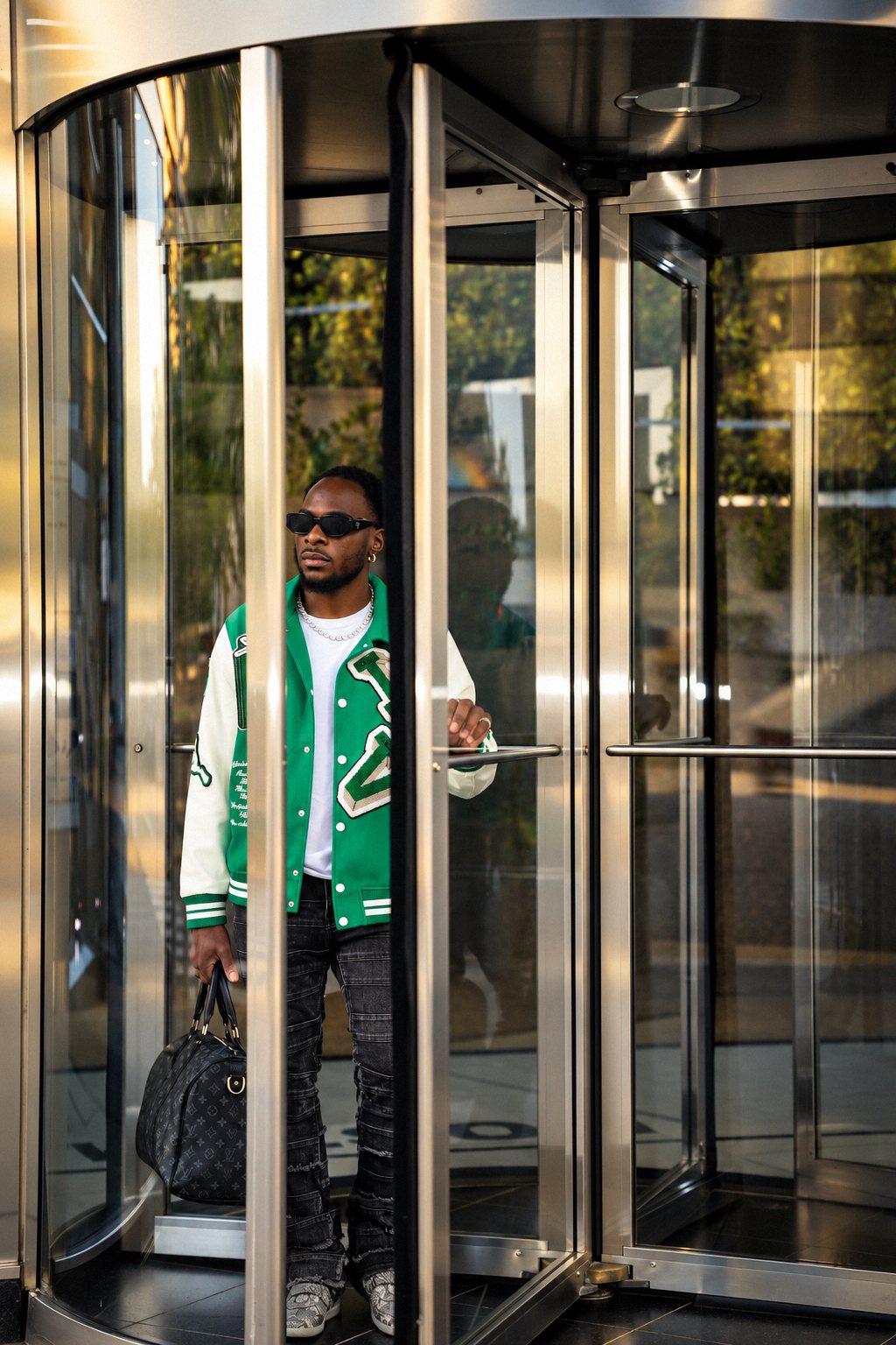 Man in a varsity jacket framed inside a revolving glass door