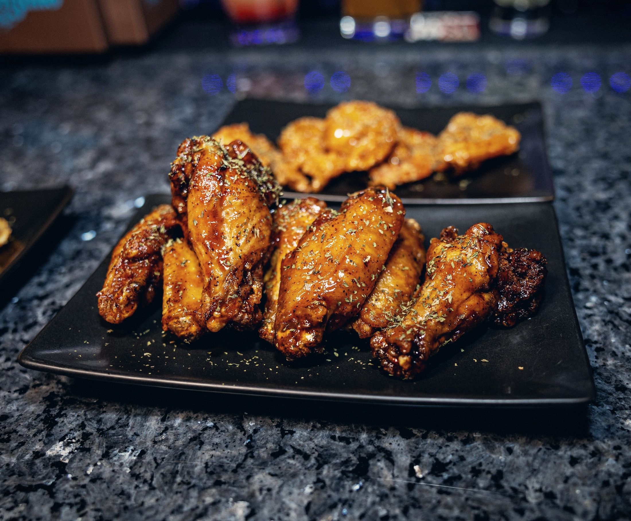 Glazed chicken wings on a black plate