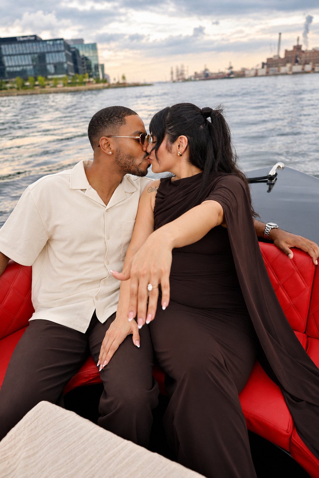 Newly engaged couple kissing as she shows the ring