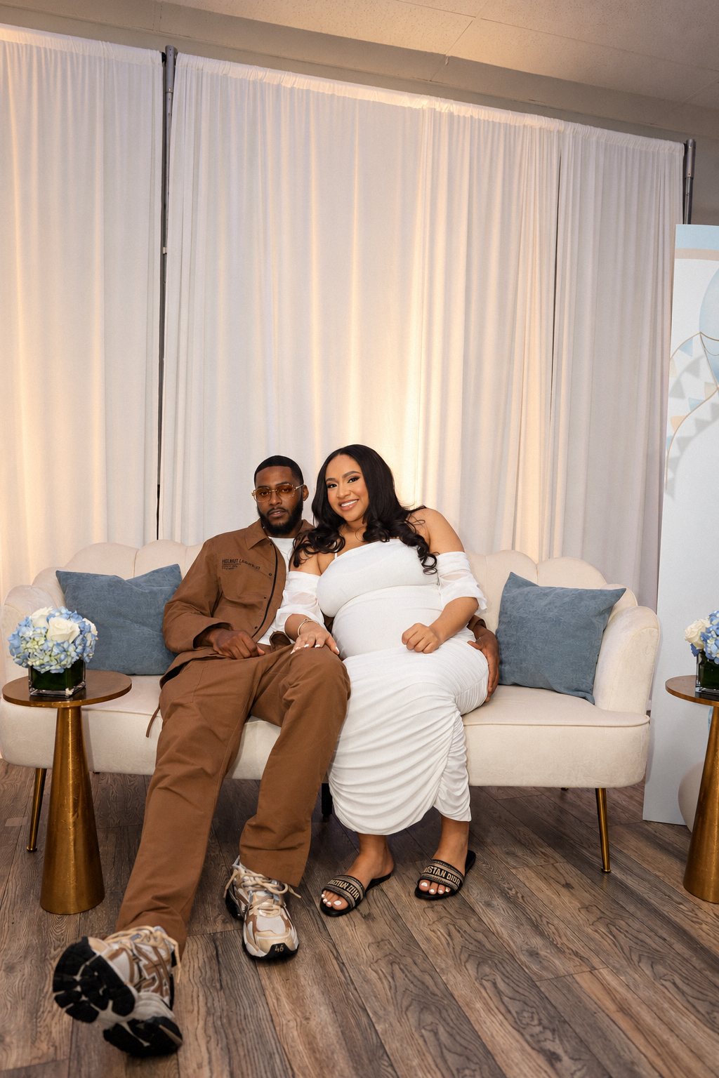 Expecting couple on a cream sofa at their baby shower