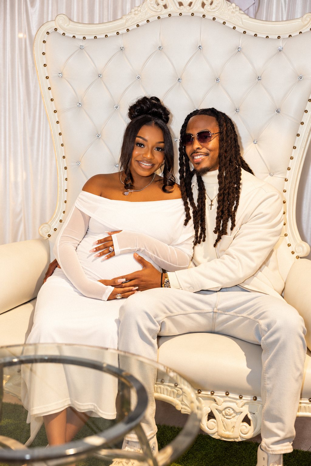 Expecting couple smiling on a white throne