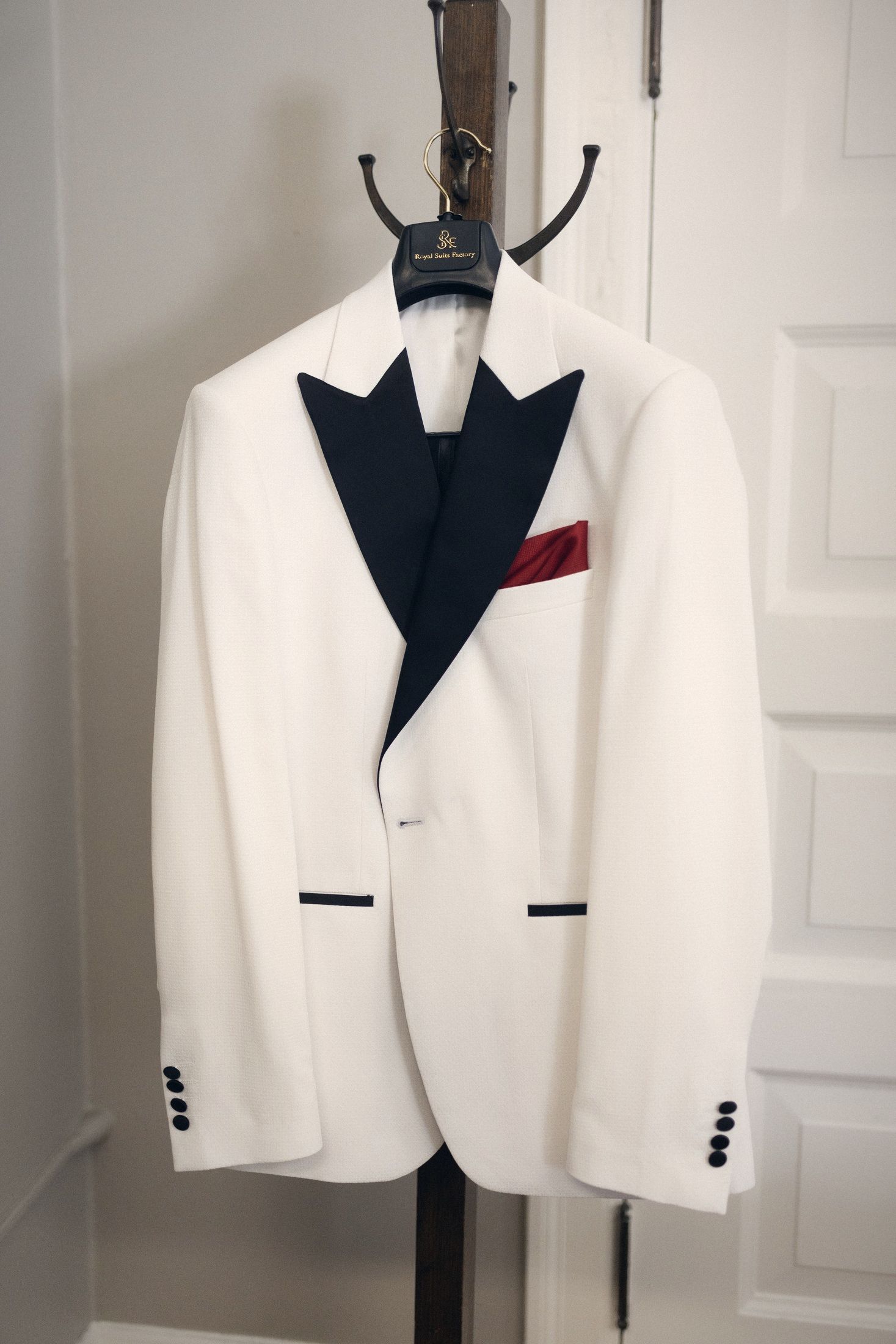 White dinner jacket with a red pocket square hanging on a door