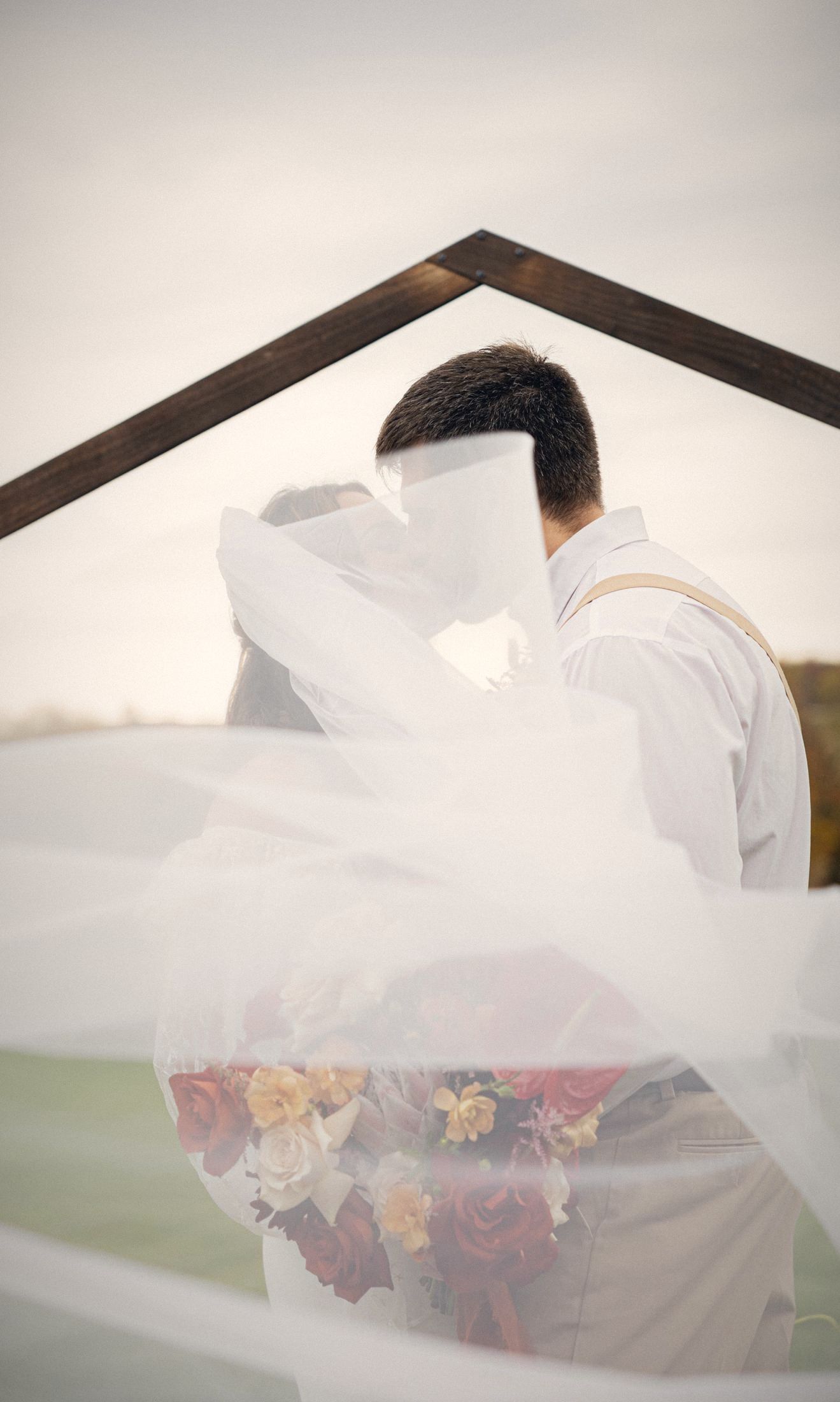 Couple kissing behind a flowing veil