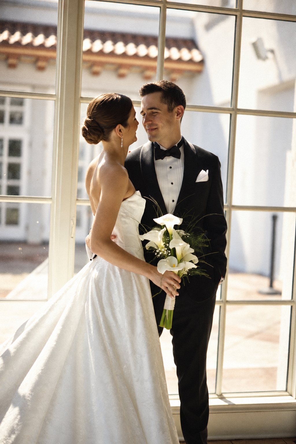 Bride and groom in black tie by a sunlit window